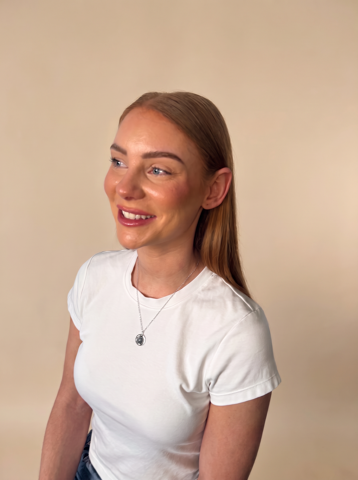 Model smiling in a white tee wearing the Rare · Timeless · True Meaning Pendant